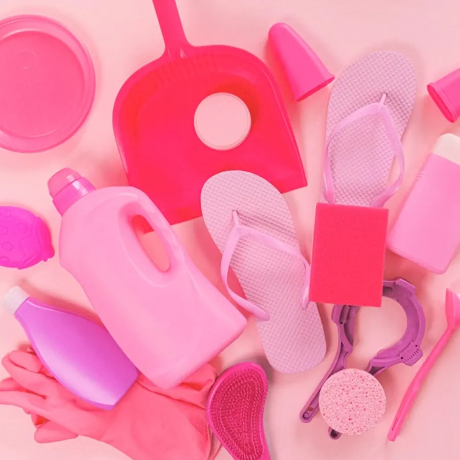 Pink cleaning supplies including a dustpan, bottles, sponges, and gloves